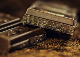 Macro shot of rich dark chocolate bars sprinkled with cocoa powder, highlighting texture and indulgence.